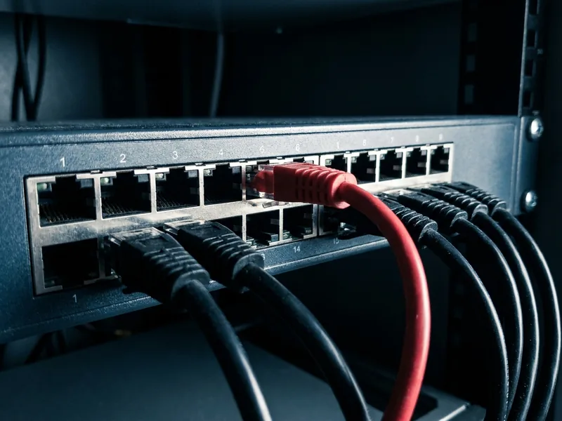 Switch de rede com cabos pretos e um único cabo vermelho conectado