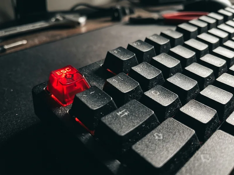 Teclado mecânico preto com a tecla Esc vermelha em destaque